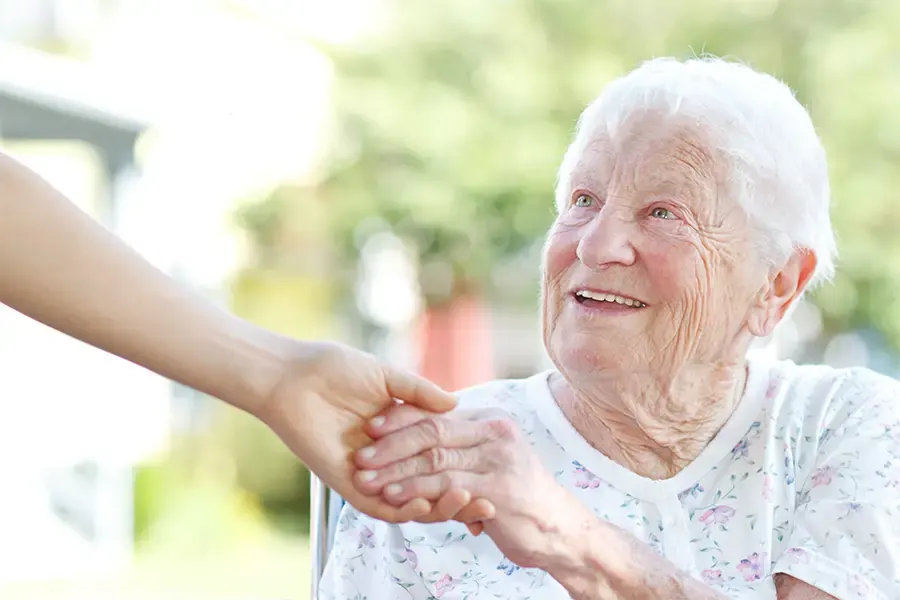 Eine ältere Dame lächelt und hält eine helfende Hand