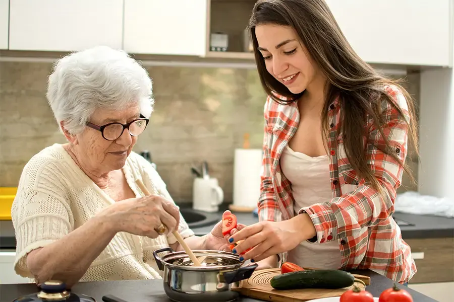 Seniorin und Betreuerin kochen gemeinsam